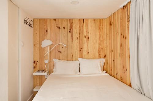 - une chambre avec un lit et un mur en bois dans l'établissement Studio Nest - Near the train to Lisbon & Sintra, à Algueirão
