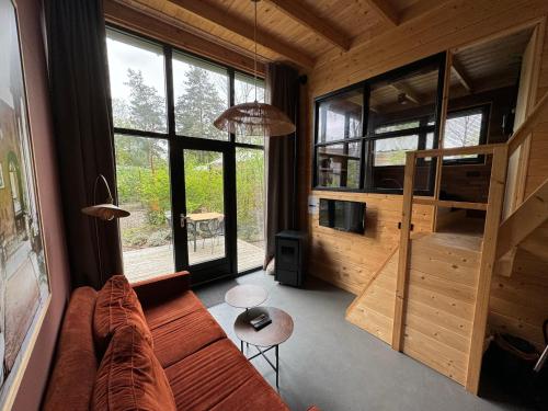 a living room with a couch and a large window at Tiny House Mayu - Veluwe Airco 4 persons in Arnhem