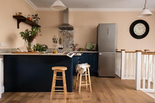 a kitchen with a refrigerator and two bar stools at Fairnington East Wing in Kelso