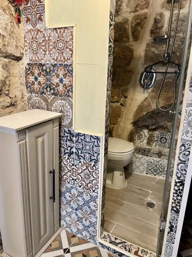 a bathroom with a toilet and tiles on the wall at Hebi house in ‘Akko