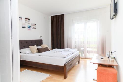 a white bedroom with a bed and a window at Apartmani Zvirac in Soko Banja