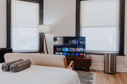 a bedroom with a bed and a flat screen tv at Chic Studio Walk to SMM SLU Hospital Grand in Tower Grove