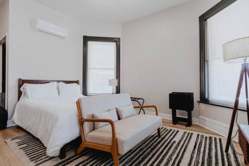 ein Schlafzimmer mit einem weißen Bett und einem Stuhl in der Unterkunft Chic Studio Walk to SMM SLU Hospital Grand in Tower Grove