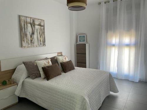 a bedroom with a large bed with white sheets and brown pillows at piso recinto ferial en teatinos in Málaga