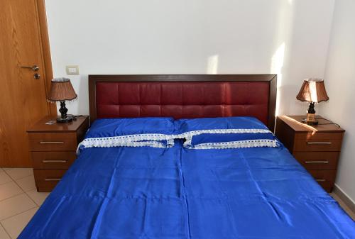 a blue bed with a red headboard and two night stands at Vila Merkuri in Vlorë