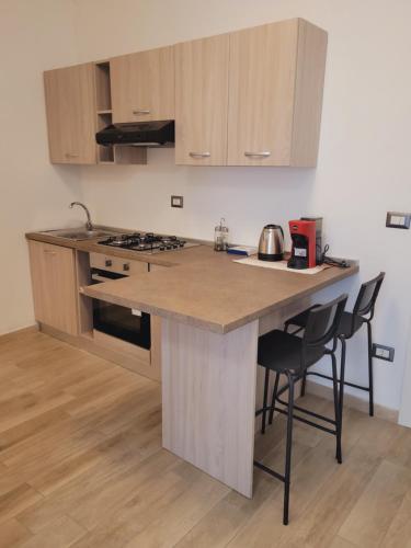 a kitchen with a island with a stove and chairs at HOUSE AIRPORT Catania in Catania