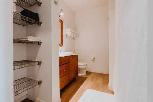 a bathroom with a sink and a toilet and shelves at Luxe 2BR-1BA Penthouse w Balcony & Pool in Tower Grove