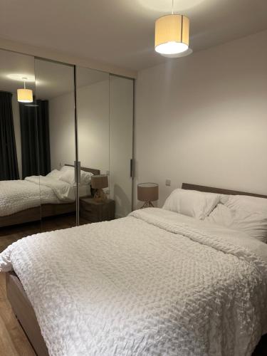 ein Schlafzimmer mit einem großen weißen Bett und einem Spiegel in der Unterkunft Simply lux apartment in London