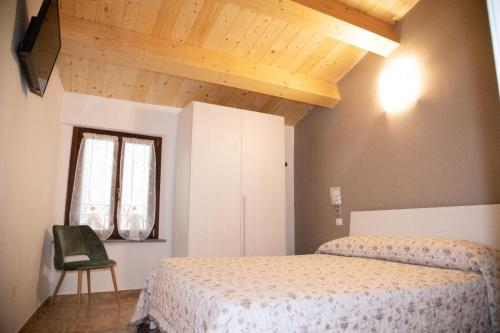 a bedroom with a bed and a window and a chair at LA BRAVERIA in Urbania