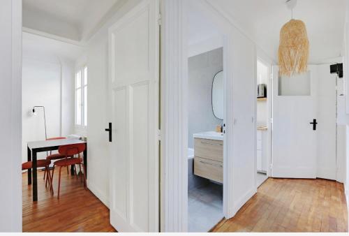 een witte hal met een bureau en een tafel bij Appartement, cœur des Batignolles Montmartre in Parijs