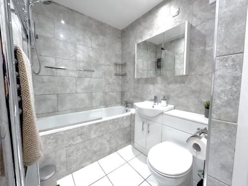 a bathroom with a toilet and a sink and a tub at Contemporary and Cosy Birmingham Apartment- Free Parking & Wi-FI in Birmingham