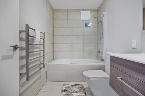 a bathroom with a tub and a toilet and a sink at Glen Townhouse with Parking and Wi-Fi in Auckland