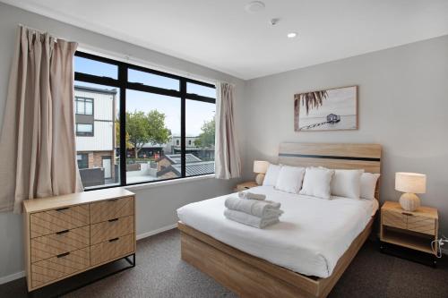 um quarto com uma cama e uma grande janela em Glen Townhouse with Parking and Wi-Fi em Auckland