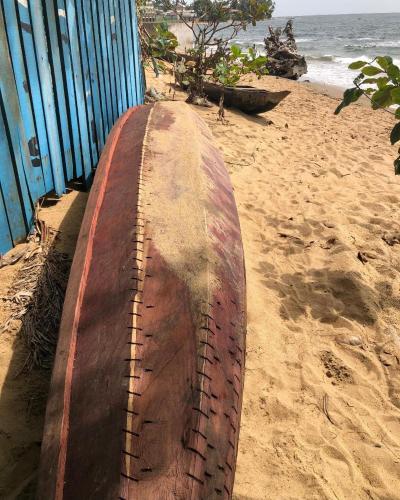 a wooden surfboard sitting on the sand on a beach at OCEAN-SI Mansion in Kribi