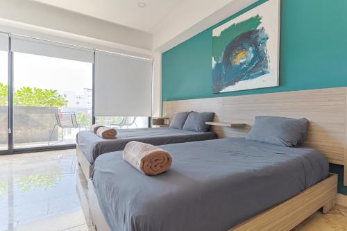 - 2 lits dans une chambre avec une grande fenêtre dans l'établissement Torre Diez Grupo Amber - Collection O, à Playa del Carmen