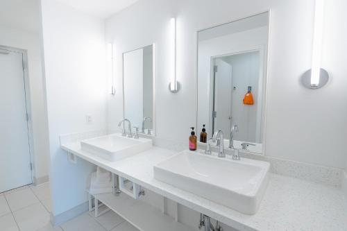 a white bathroom with two sinks and two mirrors at The Gallatin in Nashville