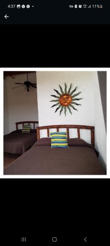 um quarto com duas camas com uma pintura de um sol na parede em Sancarlosbeach em San Carlos