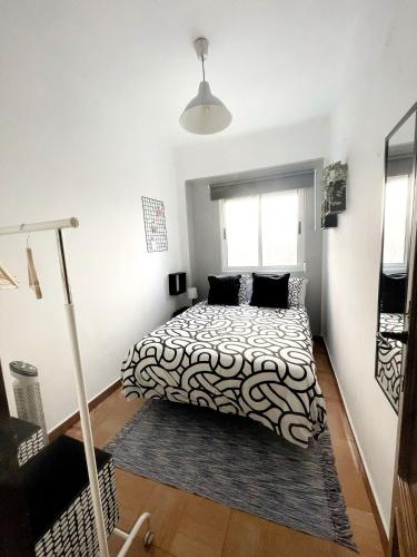 1 dormitorio con 1 cama con edredón blanco y negro en La Casita de las Hermanas, en Málaga
