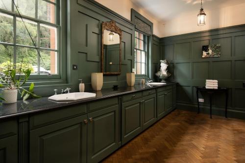 een groene badkamer met een wastafel en een spiegel bij Fairnilee House in Galashiels