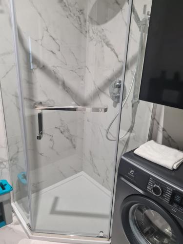 een badkamer met een douche en een wasmachine bij Apartament Kochanowskiego 10 in Nowy Sącz