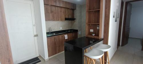 a kitchen with a black counter and white stools at Apartamento en Villeta 2 in Villeta