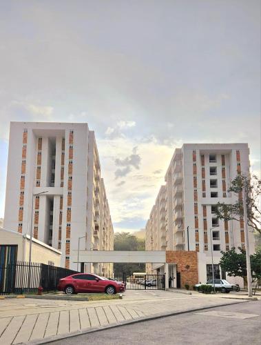 a red car parked in front of two large buildings at Apartamento en Villeta 2 in Villeta