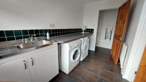 uma cozinha com um lavatório e uma máquina de lavar roupa em Tradewind, Easton Lane, Freshwater em Freshwater