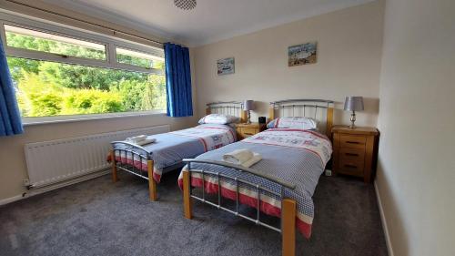 two beds in a room with a window at Tradewind, Easton Lane, Freshwater in Freshwater