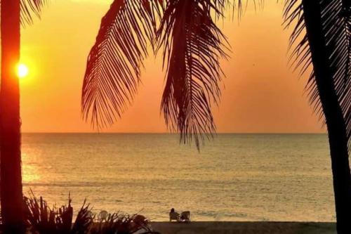 a sunset over the ocean with people on the beach at El Refugio Beach House, Bello Horizonte, Santa Marta in Playa Dormida