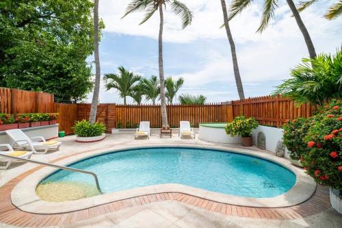 a swimming pool in a backyard with palm trees at El Refugio Beach House, Bello Horizonte, Santa Marta in Playa Dormida