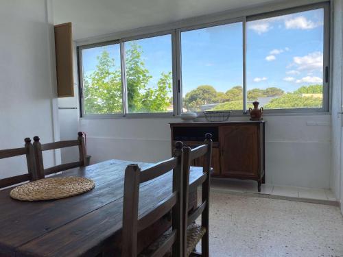 d'une salle à manger avec une table en bois et de grandes fenêtres. dans l'établissement Appartement spacieux 76m², proche Thermes et centre, 2 ch, parking, WIFI, Balaruc-les-Bains - FR-1-553-226, à Balaruc-les-Bains