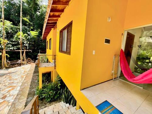 a yellow house with a hammock on the side of it at Pousada do Riacho Trindade in Trindade