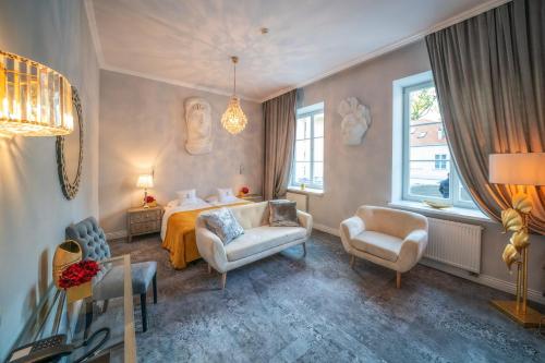 - une chambre avec un lit, un canapé et des chaises dans l'établissement Hotel Pałac Alexandrinum, à Krubki