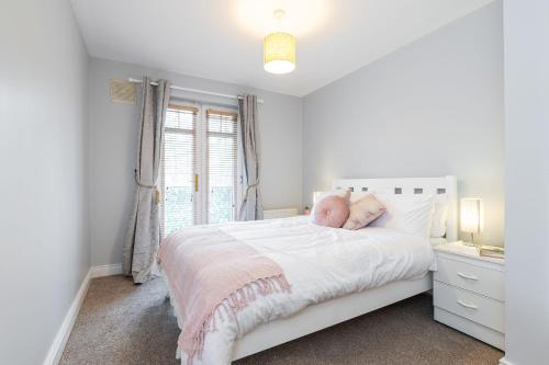 a white bedroom with a white bed and a window at Holywell Rise Swords in Swords