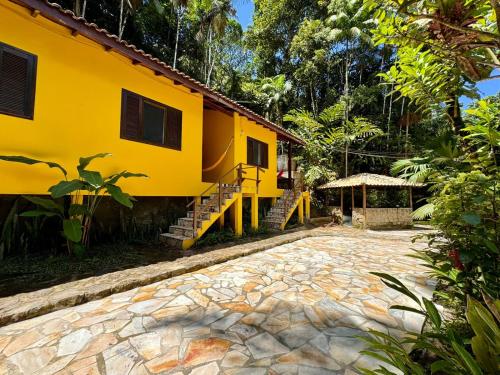 a yellow house with a stone path in front of it at Pousada do Riacho Trindade in Trindade