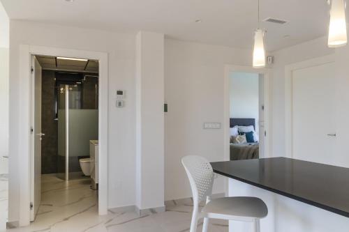 une cuisine avec des murs blancs, un comptoir noir et des chaises dans l'établissement Top floor Pink Vistagolf - Winter by the sea, à San Miguel de Salinas