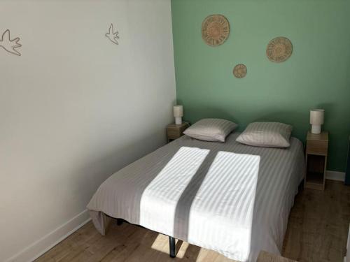 a bedroom with a bed with white sheets and green walls at Soleil urbain in Périgueux