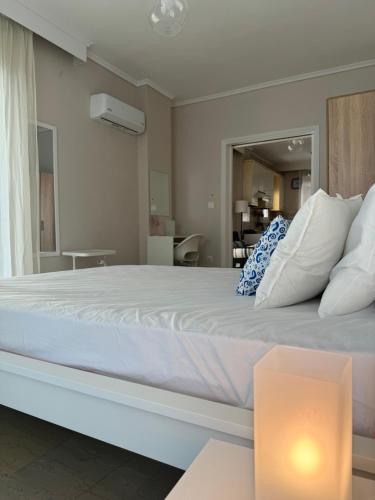 um quarto com uma grande cama branca e uma mesa em POSEIDON'S APARTMENT IN PERAIA - SUPERIOR BY THE SEA em Perea