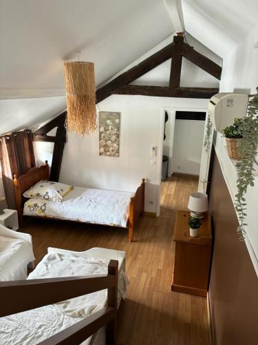 une chambre avec deux lits et un plafond avec poutres dans l'établissement Gîte dans ferme rénovée 4-5 personnes, à Aubarède