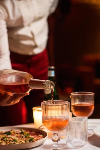 a person is pouring wine into a glass at La Suite Hotel Agadir Adults Only in Agadir