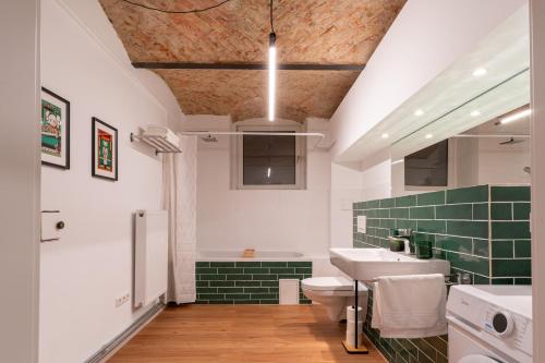 baño con lavabo, aseo y azulejos verdes en bevoflats - Zentrales Apartment im Bergmannkiez, en Berlín