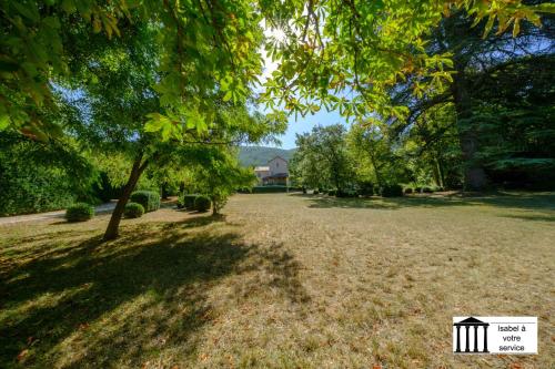 un champ avec des arbres et une maison en arrière-plan dans l'établissement Souterrain Villa Aulan, 6 personen, à Montbrun-les-Bains