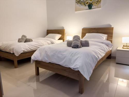 - 2 lits dans une chambre avec des draps et des oreillers blancs dans l'établissement Hillcrest 3 Bedroom Apartment, à Mellieħa