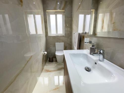 La salle de bains blanche est pourvue d'un lavabo et de toilettes. dans l'établissement Hillcrest 3 Bedroom Apartment, à Mellieħa