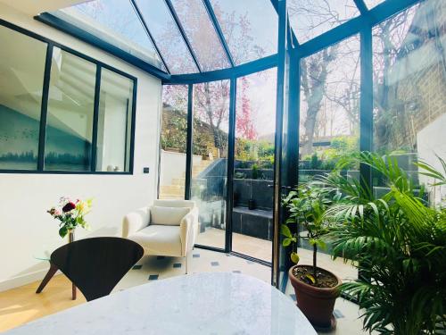 a glass conservatory with a white table and chairs and plants at Luxe 10 min Paris - Feifei's Home & Spa in Asnières-sur-Seine