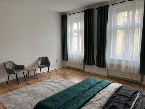 a bedroom with a bed and a table and two windows at Apartmán Teplice in Teplice