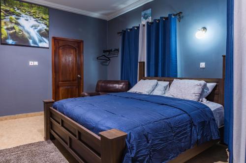 a bedroom with blue walls and a bed and a chair at BlueGreen GuestHouse in Accra