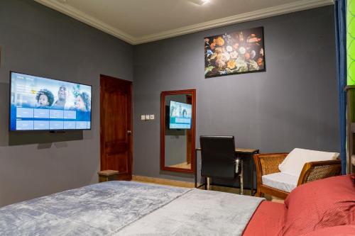 a bedroom with a bed and a flat screen tv at BlueGreen GuestHouse in Accra
