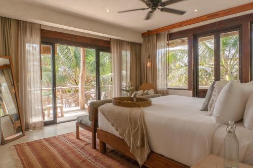 1 dormitorio con 1 cama blanca grande y ventanas grandes en Aldea Canzul Tulum en Tulum