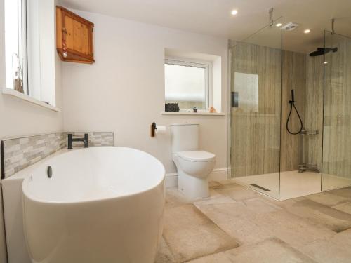 a bathroom with a tub and a toilet and a shower at Woodbine Cottage in Falmouth